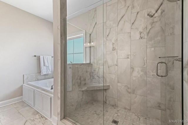 bathroom with a stall shower, marble finish floor, baseboards, and a garden tub