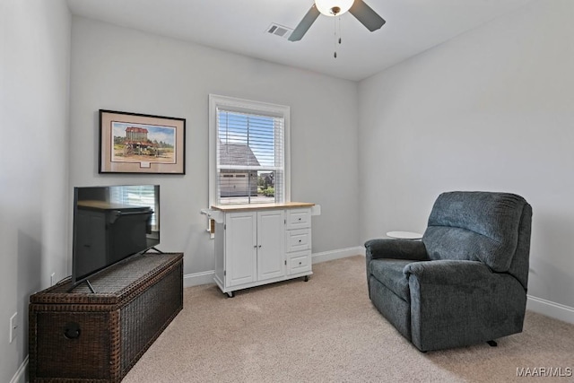 sitting room with baseboards, visible vents, ceiling fan, and light colored carpet