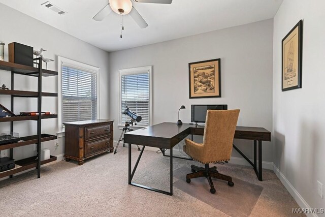 home office featuring light colored carpet, visible vents, baseboards, and a ceiling fan