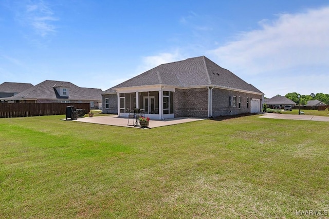 rear view of property with a lawn, fence, a patio, an attached garage, and a sunroom