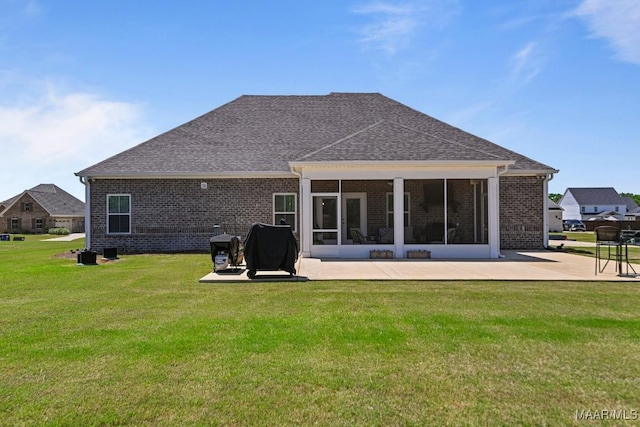 back of property with a yard, a patio, and brick siding