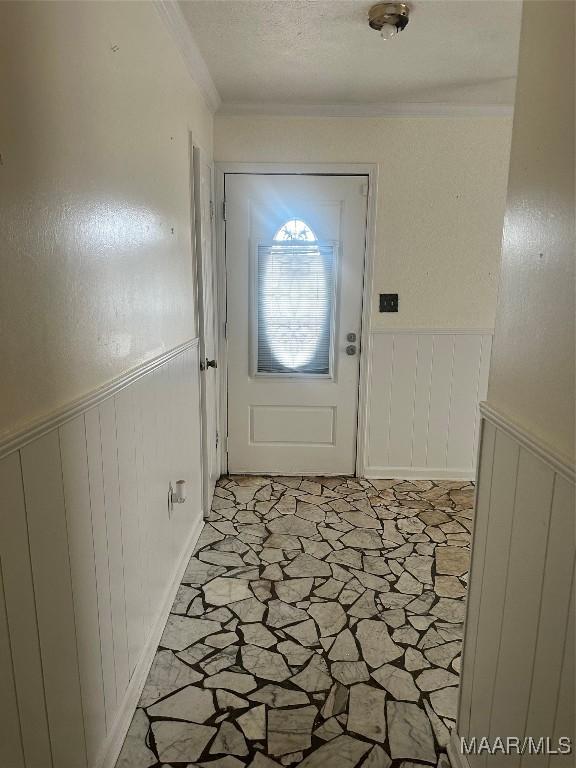 5545 E Shades Valley Dr, Montgomery, AL 36108 - doorway with wainscoting, a decorative wall, stone finish flooring, and ornamental molding