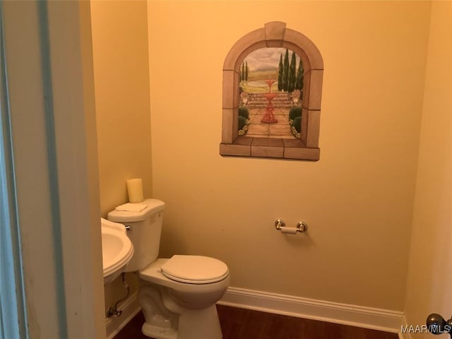 half bath featuring toilet, baseboards, and wood finished floors