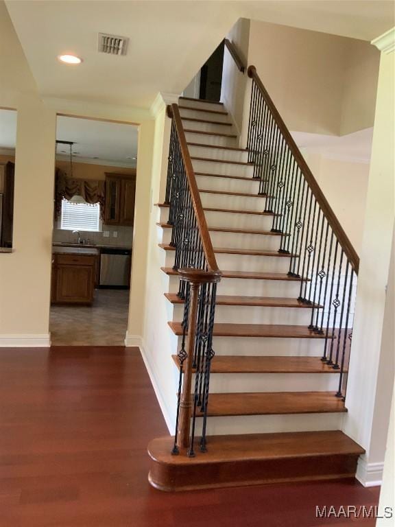 stairway featuring wood finished floors, visible vents, baseboards, and recessed lighting