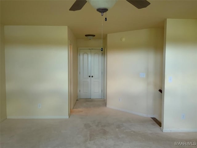 carpeted empty room with baseboards and a ceiling fan