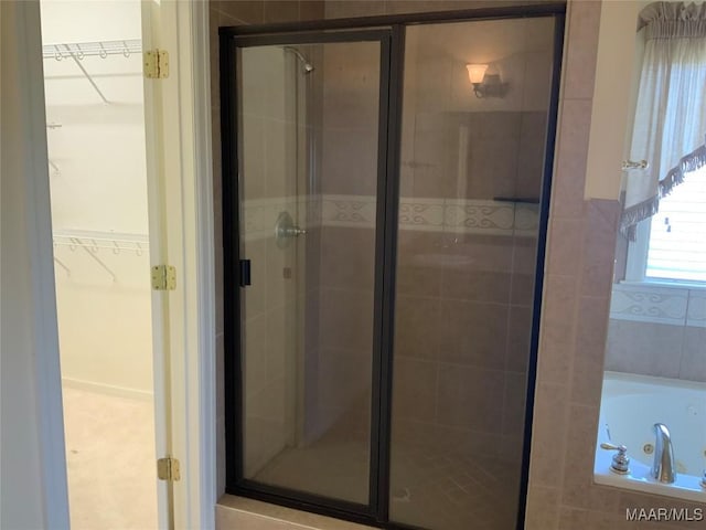 full bath featuring a shower stall, a spacious closet, and a whirlpool tub
