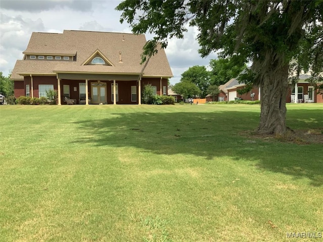 back of property with a yard and roof with shingles