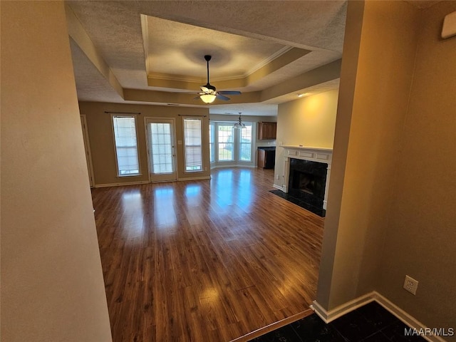1946 Regent Rd, Prattville, AL 36066 - unfurnished living room with a ceiling fan, a tray ceiling, a textured ceiling, a fireplace with flush hearth, and dark wood-type flooring