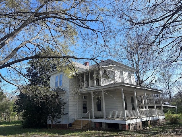 view of front of house featuring a porch, a balcony, and a chimney