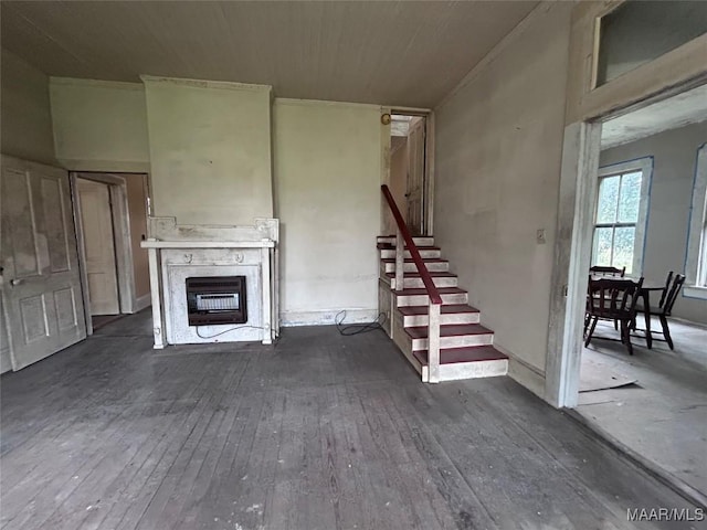 unfurnished living room with dark wood finished floors, a fireplace, heating unit, and stairway
