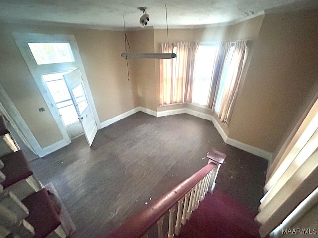 unfurnished dining area featuring baseboards and dark wood finished floors