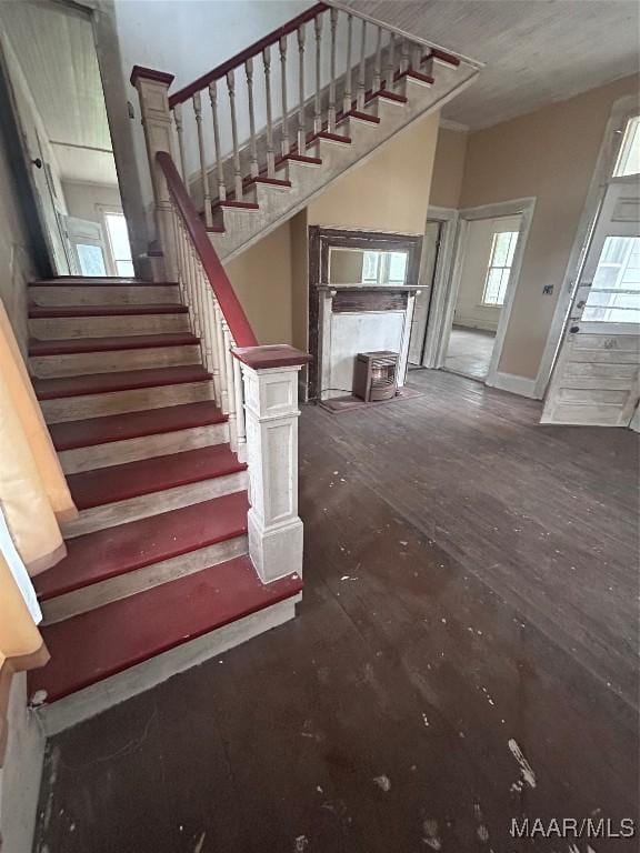 staircase featuring wood finished floors, baseboards, and a wood stove
