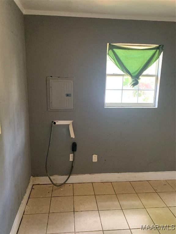 spare room with electric panel, baseboards, ornamental molding, and light tile patterned flooring