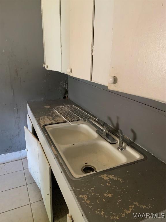 kitchen view of white cabinets, a sink, baseboards, and dark countertops