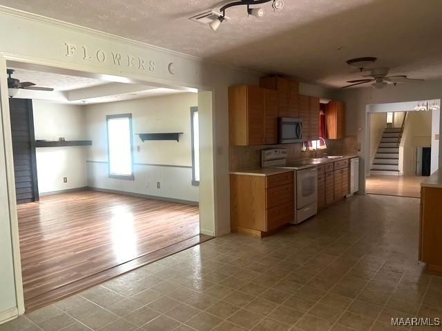 kitchen featuring white electric range oven, ceiling fan, brown cabinetry, black microwave, and a textured ceiling