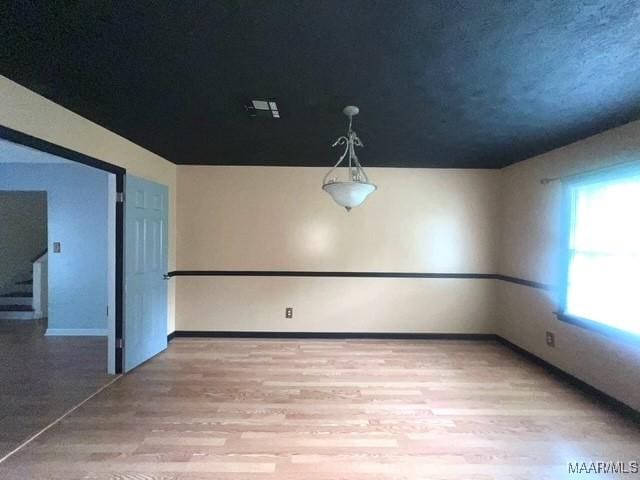 unfurnished room with light wood-type flooring and baseboards