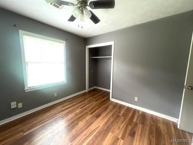 unfurnished bedroom with baseboards, wood finished floors, a closet, and a ceiling fan