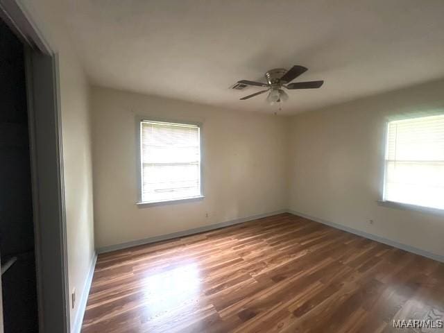 spare room with wood finished floors, ceiling fan, and baseboards