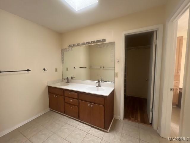 bathroom featuring tile patterned floors, baseboards, and double vanity