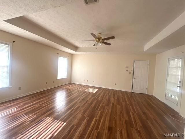 spare room with a tray ceiling, wood finished floors, baseboards, and a ceiling fan