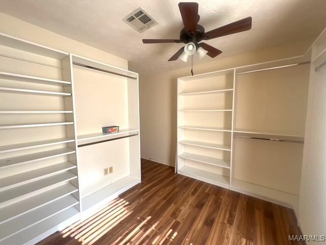 unfurnished bedroom with dark wood-style flooring, a closet, and ceiling fan
