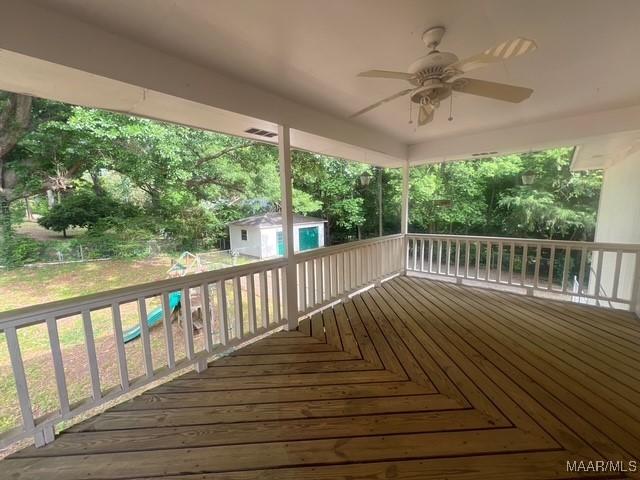 wooden deck with ceiling fan, a storage unit, and an outdoor structure