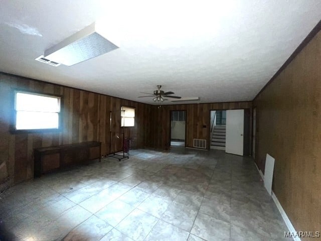 654 Old Jasmine Hill Rd, Wetumpka, AL 36093 - unfurnished living room with wood walls, ceiling fan, and stairs