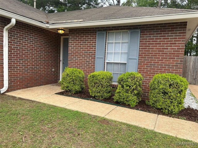 1348 Whisperwood Ct, Montgomery, AL 36117 - view of exterior entry featuring brick siding, fence, and roof with shingles