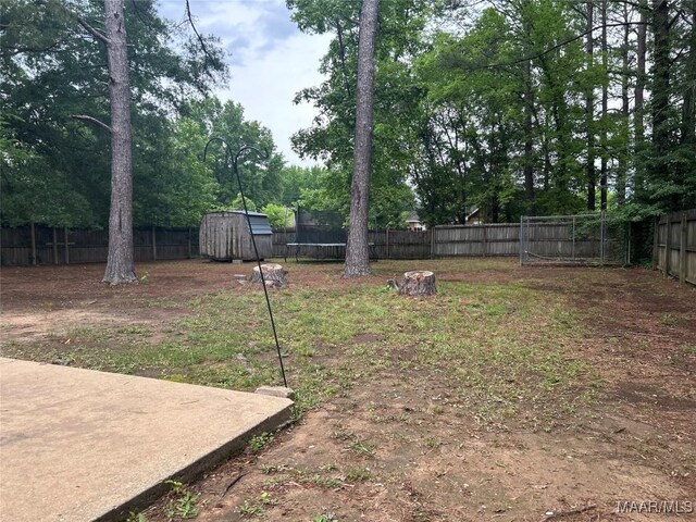 1348 Whisperwood Ct, Montgomery, AL 36117 - fenced backyard with a trampoline, a shed, an outdoor structure, and view of scattered trees