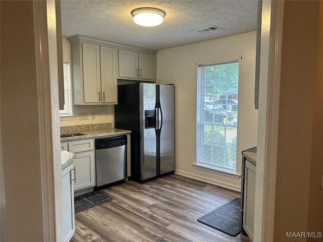 1348 Whisperwood Ct, Montgomery, AL 36117 - kitchen with appliances with stainless steel finishes, a textured ceiling, wood finished floors, light stone countertops, and baseboards