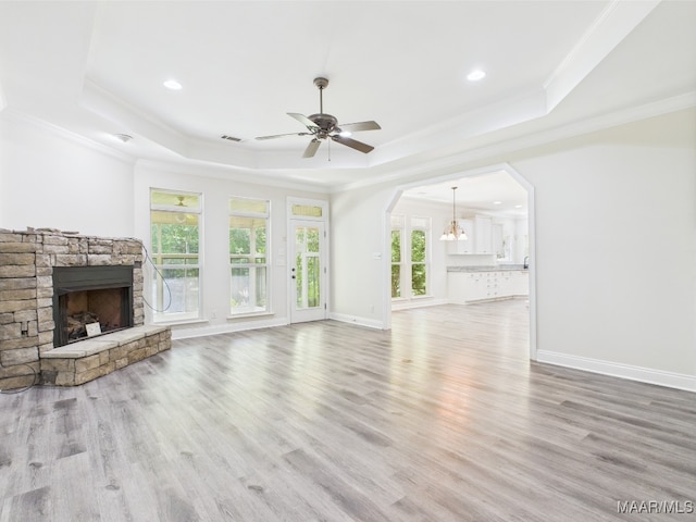 175 Rosemere Dr, Tallassee, AL 36078 - unfurnished living room with a tray ceiling, a stone fireplace, crown molding, arched walkways, and ceiling fan