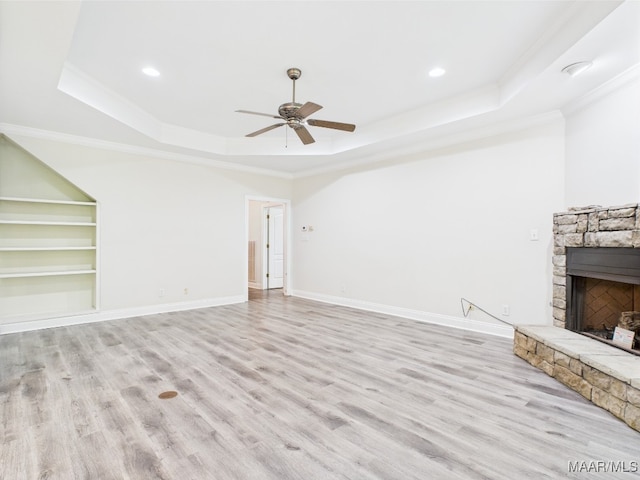 175 Rosemere Dr, Tallassee, AL 36078 - unfurnished living room with a raised ceiling, a stone fireplace, crown molding, light wood-style floors, and a ceiling fan