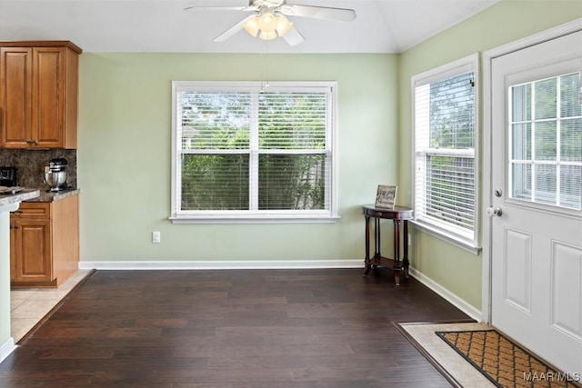 unfurnished dining area featuring wood finished floors, ceiling fan, lofted ceiling, and baseboards