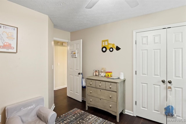 bedroom featuring dark wood-type flooring, a ceiling fan, a closet, baseboards, and a textured ceiling