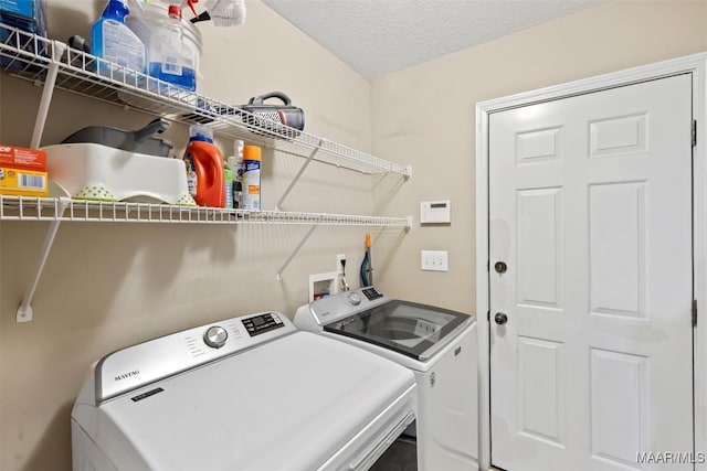 washroom featuring washing machine and clothes dryer and a textured ceiling