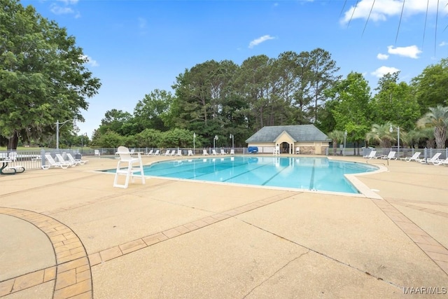 community pool featuring fence, a patio area, and view of scattered trees