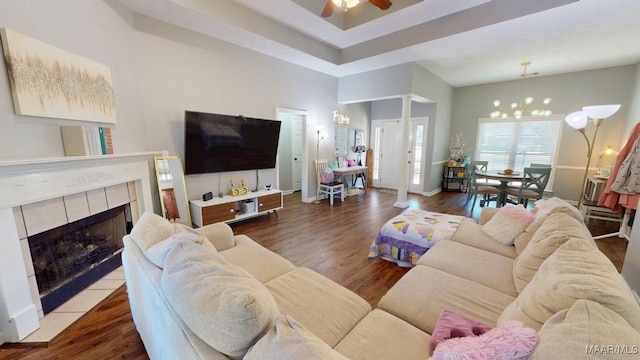 living room featuring ceiling fan, a chandelier, wood finished floors, and a tiled fireplace