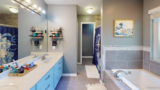 bathroom with tile patterned floors, double vanity, a bath, a textured ceiling, and baseboards