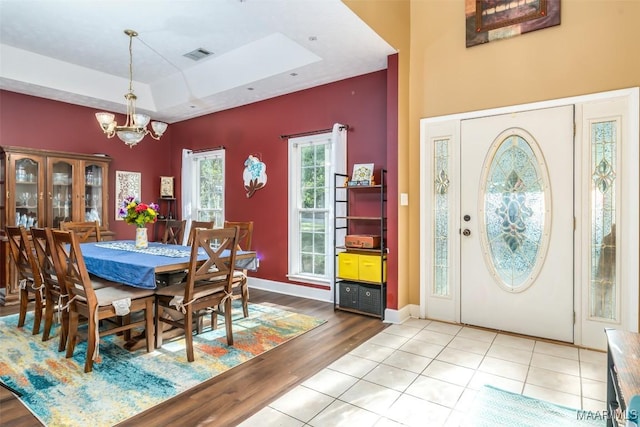 dining area with a chandelier, wood finished floors, a tray ceiling, and baseboards