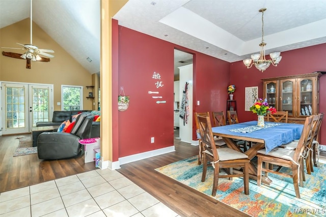 dining area featuring ceiling fan, a chandelier, wood finished floors, baseboards, and high vaulted ceiling