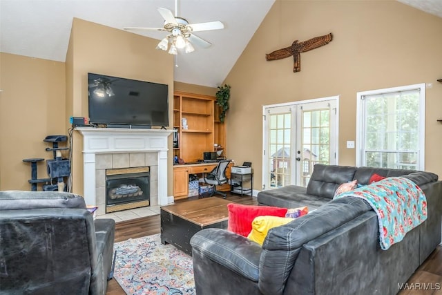 living area featuring high vaulted ceiling, a ceiling fan, wood finished floors, a desk, and a tiled fireplace