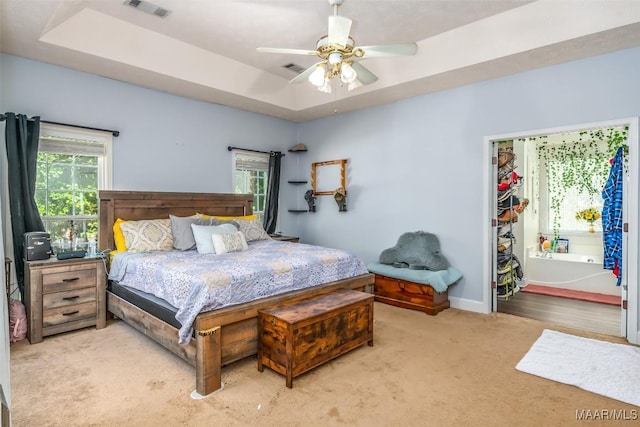 bedroom featuring carpet, a tray ceiling, baseboards, and a ceiling fan