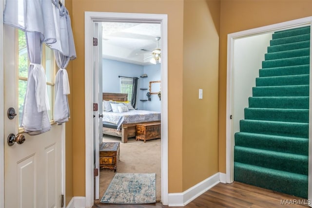 foyer featuring ceiling fan, baseboards, stairs, and wood finished floors