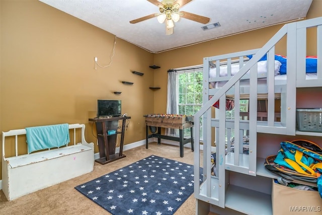recreation room with carpet floors, ceiling fan, baseboards, and a textured ceiling