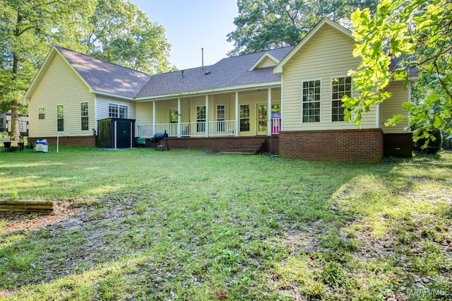 rear view of house with a storage shed, a lawn, an outdoor structure, a shingled roof, and covered porch