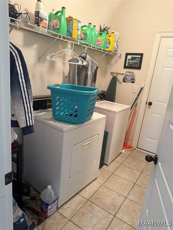 laundry room with washing machine and clothes dryer and light tile patterned floors