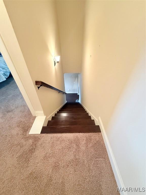 staircase featuring carpet floors and baseboards