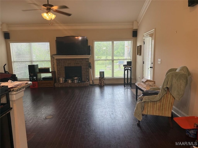 living room featuring wood-type flooring, a ceiling fan, a fireplace, crown molding, and baseboards