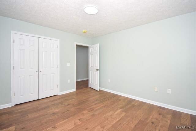 6790 Upper River Rd, Tallassee, AL 36078 - unfurnished bedroom featuring wood finished floors, baseboards, a textured ceiling, and a closet