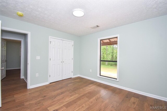 6790 Upper River Rd, Tallassee, AL 36078 - unfurnished bedroom featuring wood finished floors, baseboards, a closet, and a textured ceiling